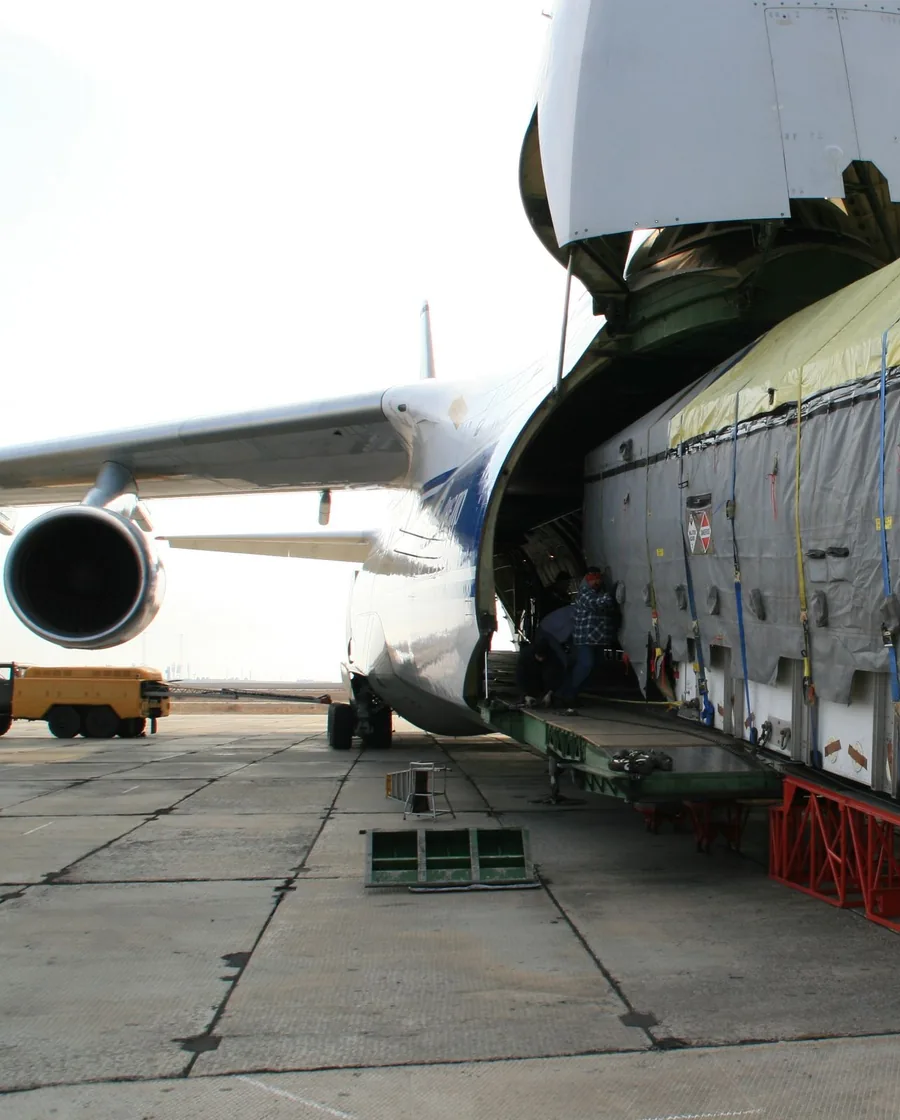 Large heavy-lift freighter with open nose door being loaded with oversized cargo on the tarmac