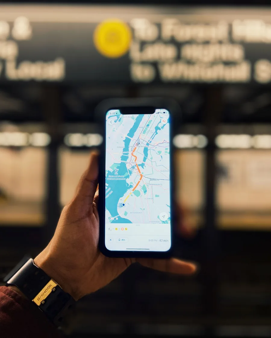 A person's hand holding a smartphone displaying a street map for navigation, vertical framing outdoors