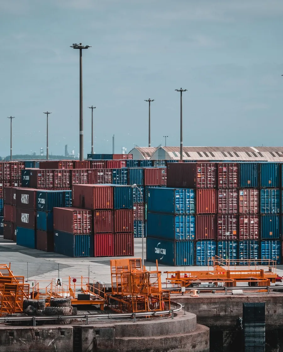 Stacked steel intermodal shipping containers viewed close up at a port terminal.