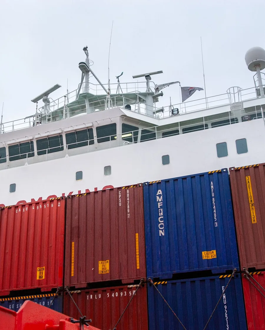 Colorful shipping containers stacked several high against a clear blue sky at a port