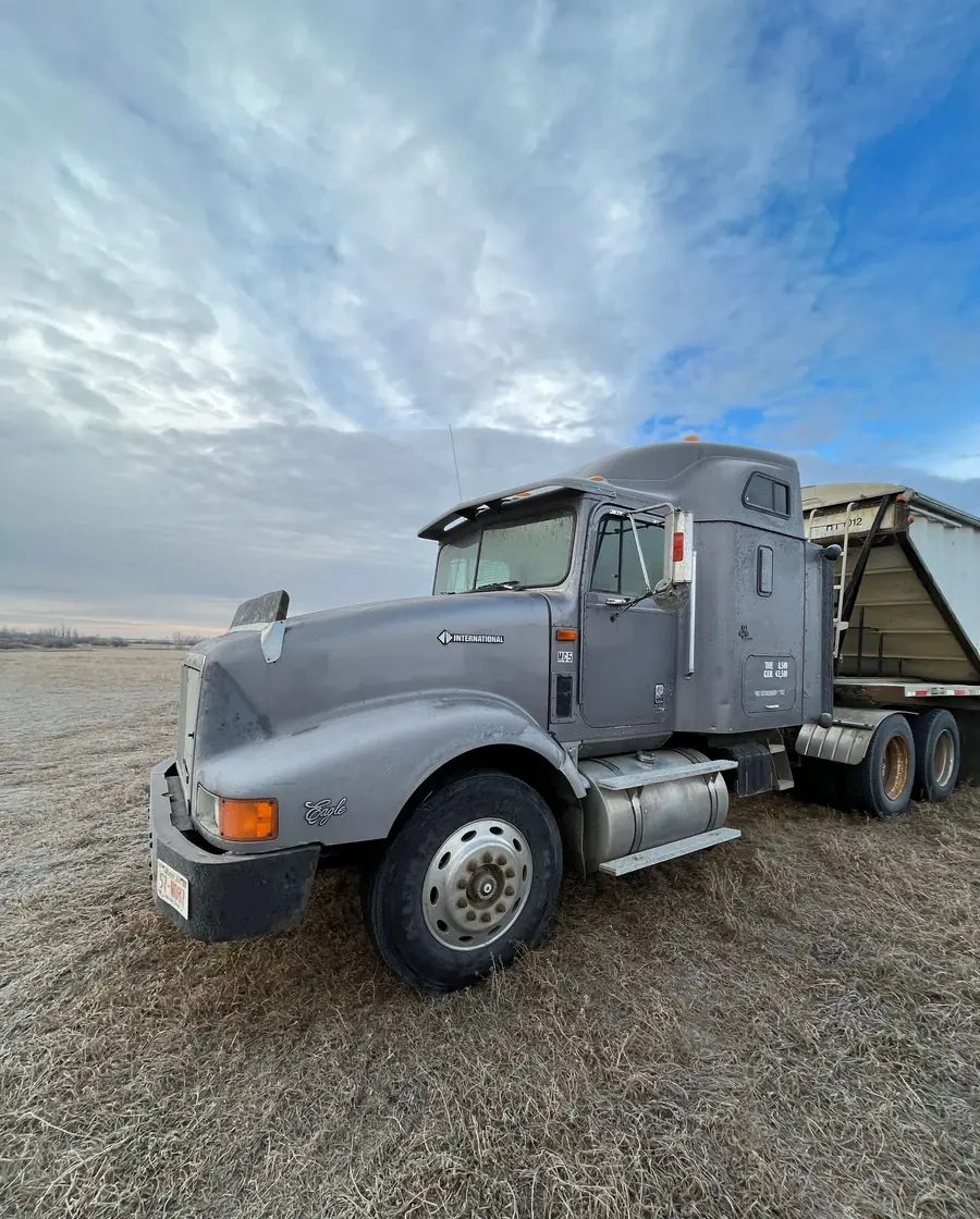 A semi truck traveling on an open highway under a blue sky