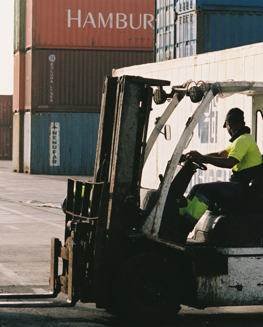 A forklift moving shipping containers at a transshipment port terminal