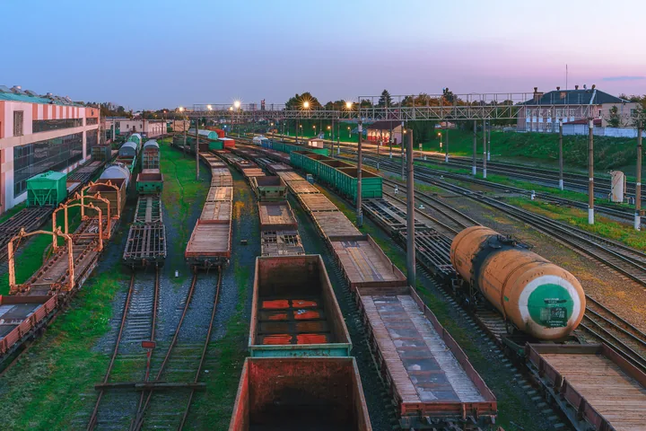 A cargo train loaded with stacked shipping containers at a rail terminal on a clear day.