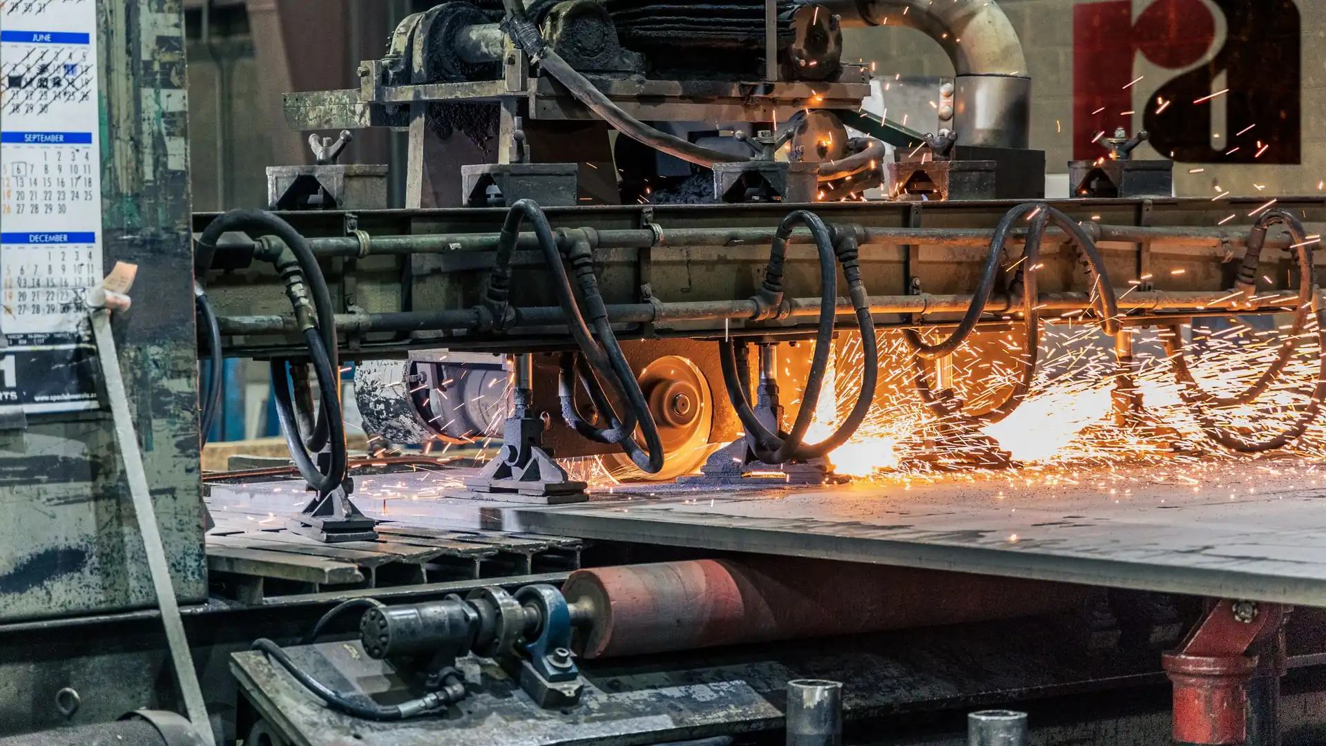 Industrial machinery on a factory floor performing metal fabrication and welding work with visible sparks.