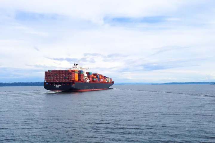 A fully loaded container ship sailing across open ocean water