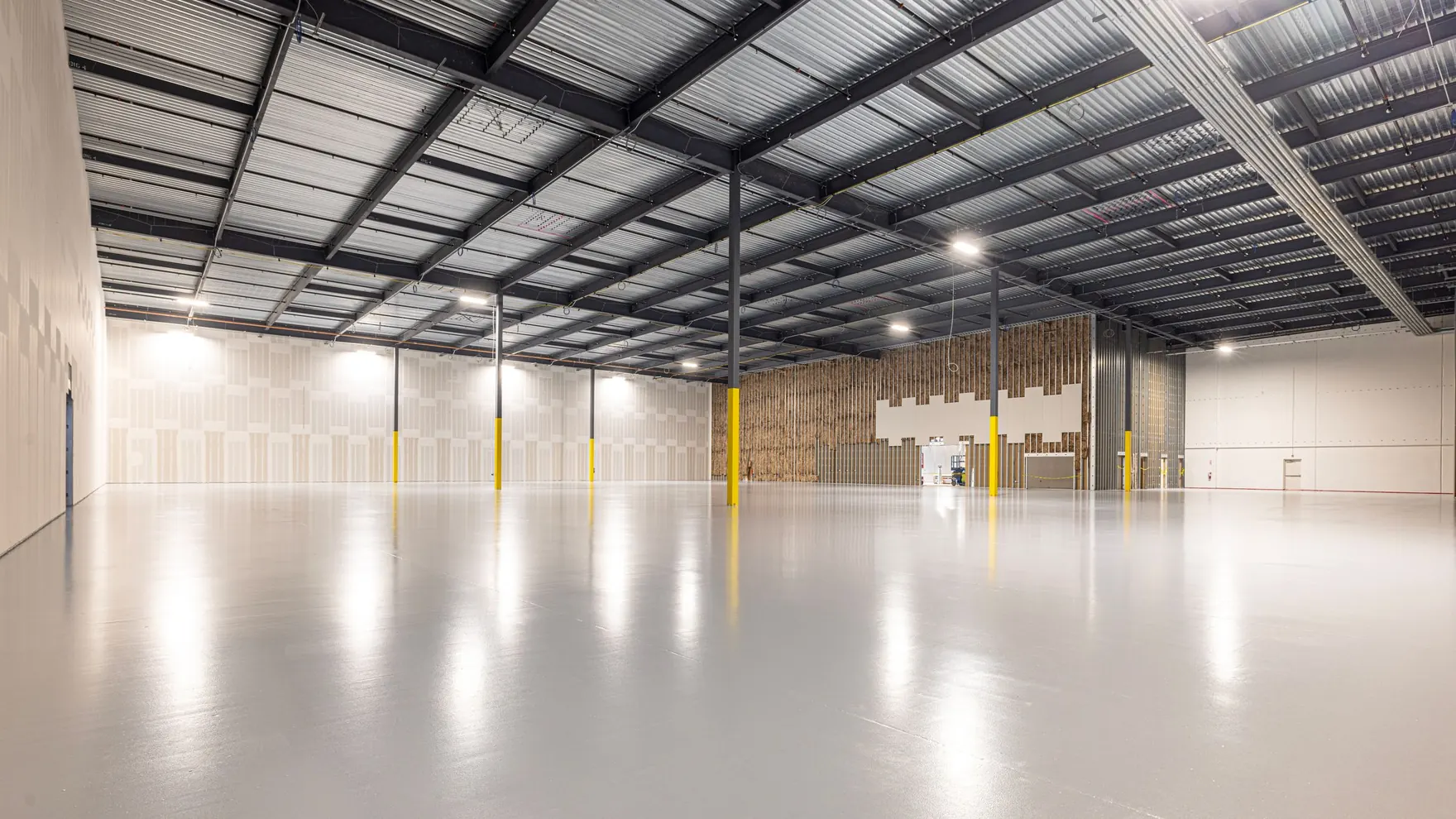 A spacious modern warehouse interior with high steel racking and wide aisles
